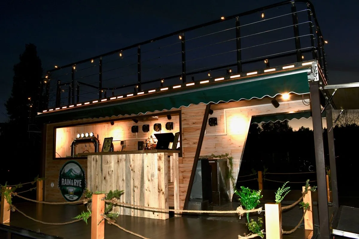 The two story mobile bar lit by string lights against a night sky