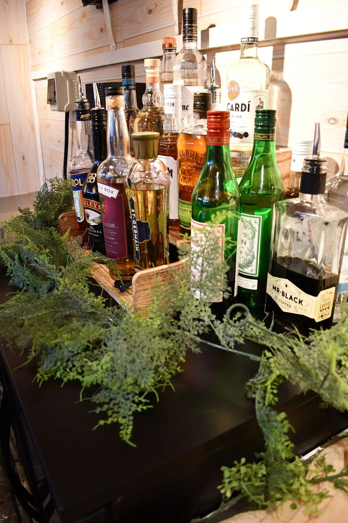 Spirit bottles arranged on the bar with greenery around them